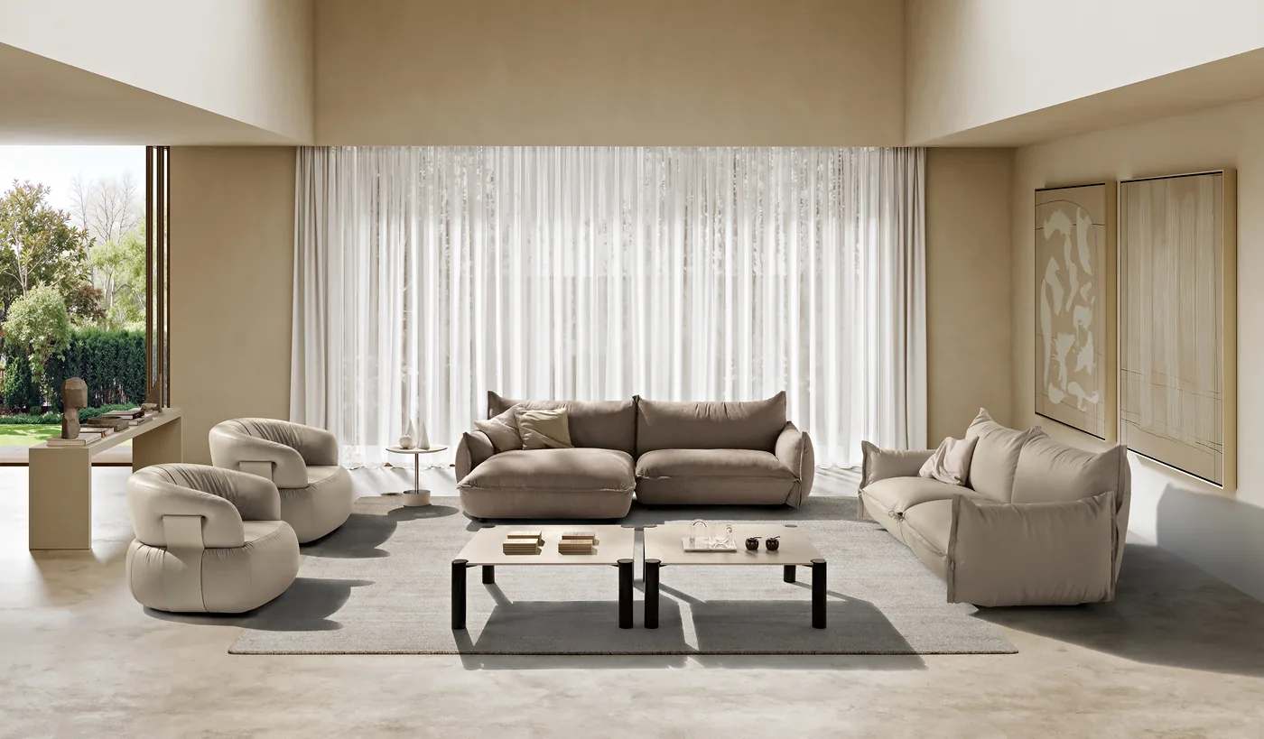 Salon en tissu beige aux formes souples : canapé, fauteuils et tables basses devant la baie vitrée