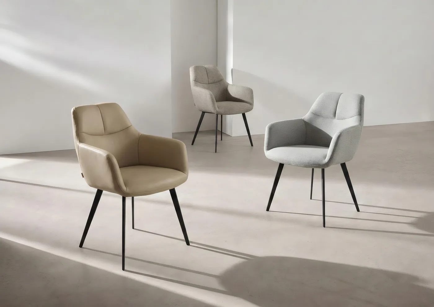 Trois chaises à accoudoirs enveloppantes, en tissu beige, gris et vert sauge, pieds noirs