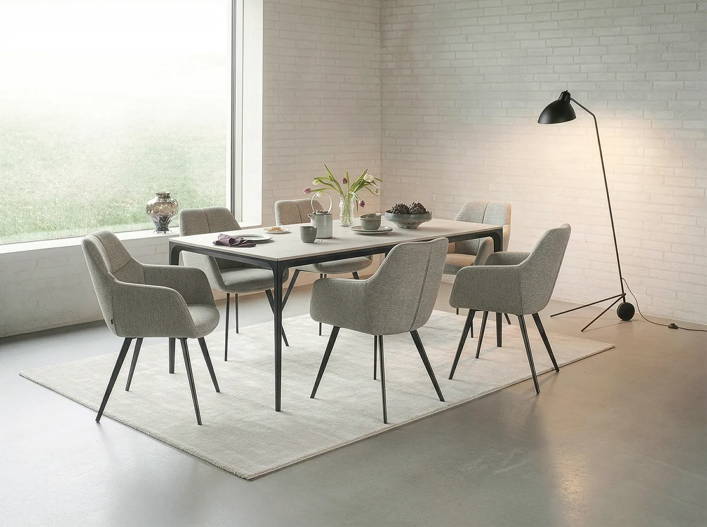 Salle à manger lumineuse : chaises à accoudoirs en tissu gris clair autour d’une table rectangulaire claire