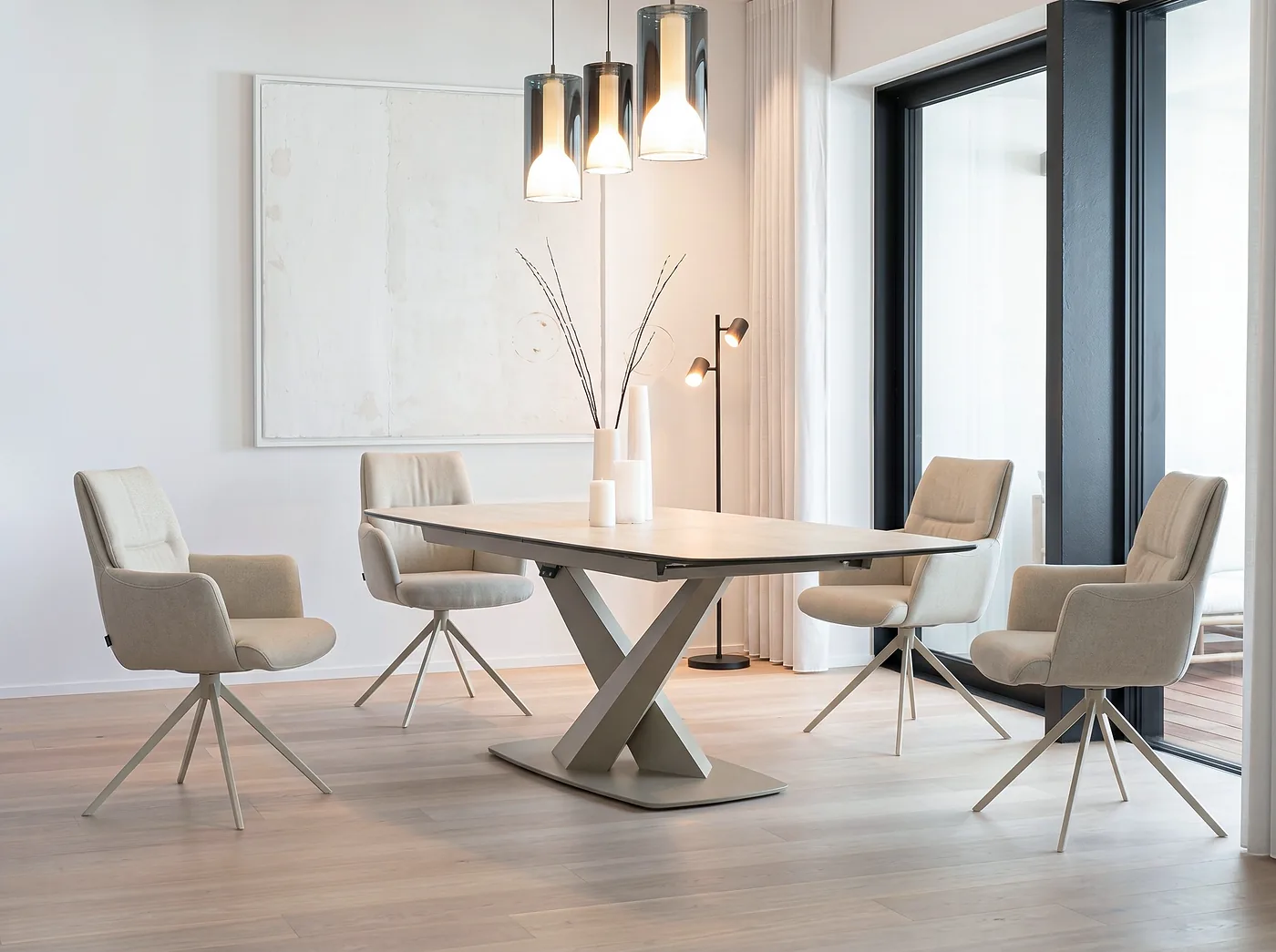 Chaises pivotantes en tissu beige, piétement en étoile, autour d’une table au pied central en X