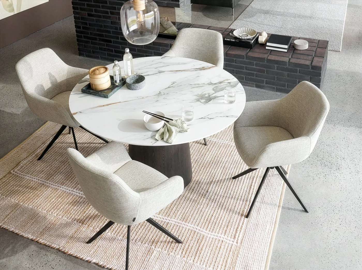 Chaises enveloppantes en tissu écru autour d’une table ronde au plateau marbré