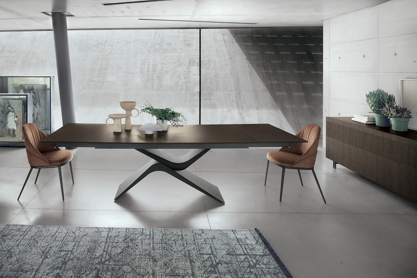 Table au plateau en bois foncé sur pied en arc, dans une pièce en béton clair