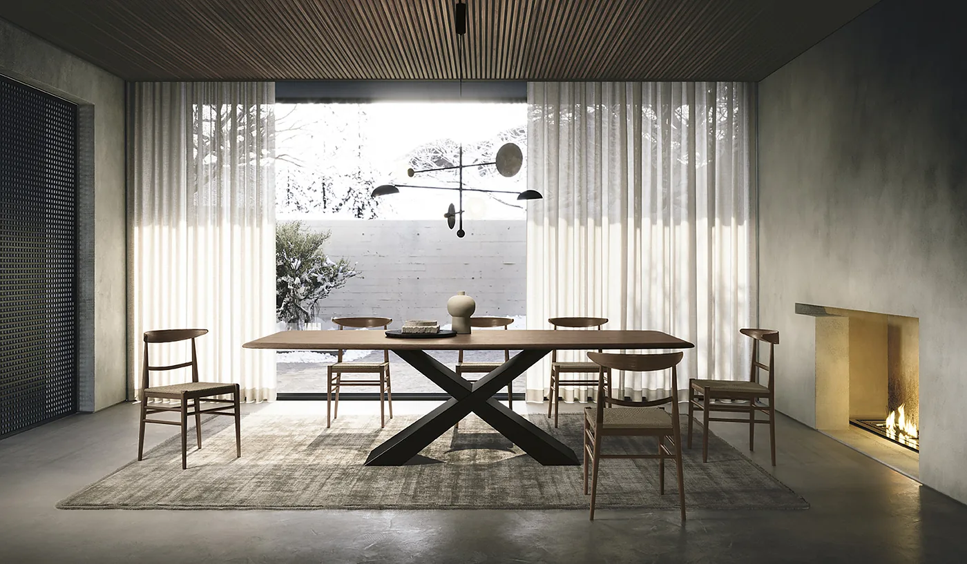 Table en céramique marbrée sur piètement croisé doré, chaises en bois, devant une cheminée