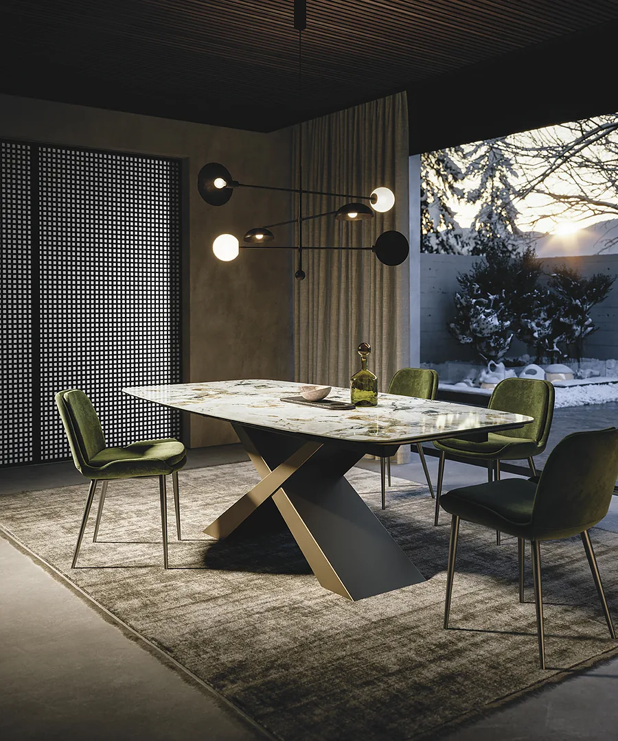 Table en céramique marbrée sur piètement croisé, chaises vertes, lumière du soir